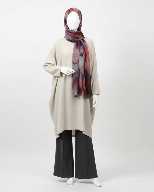 Mannequin wearing a beige long-sleeve top, black pants, and a patterned scarf on a white background